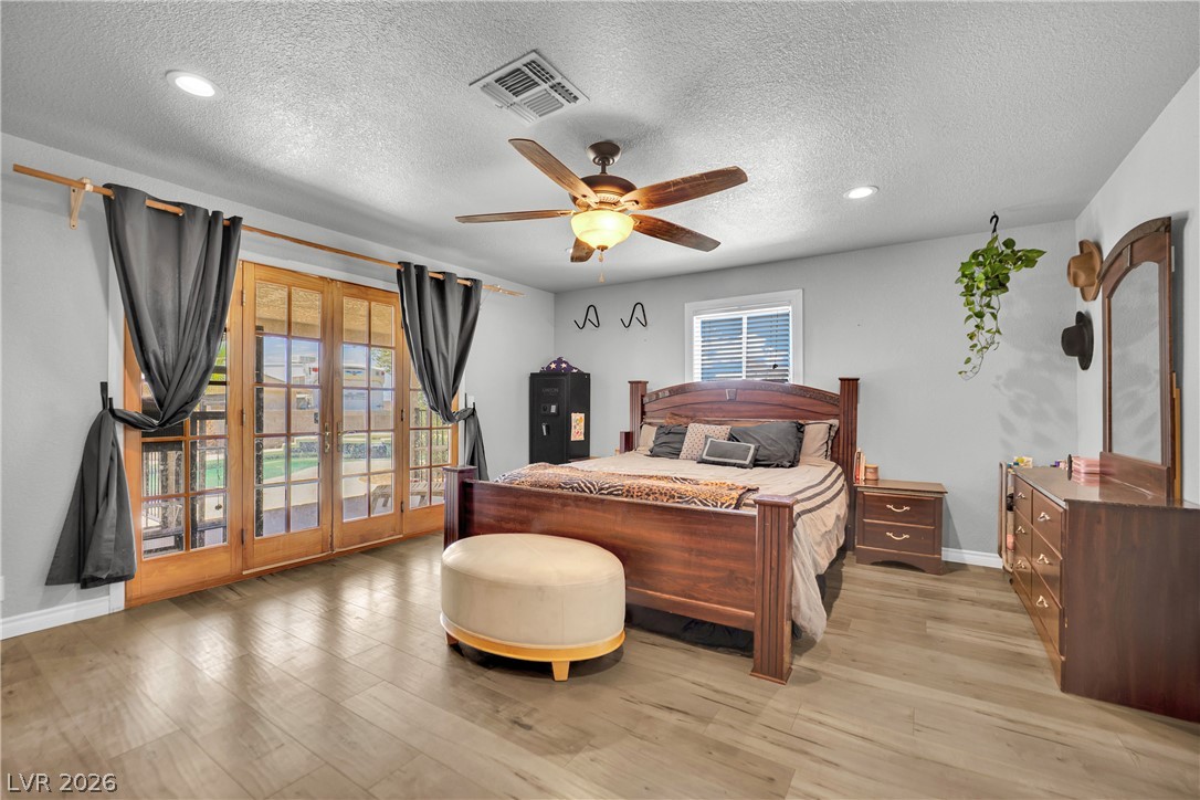 420 North Racetrack Road Henderson, NV 89015 - Photo 5 of 52 Sun-filled primary bedroom with wood flooring and direct outdoor access through French doors.