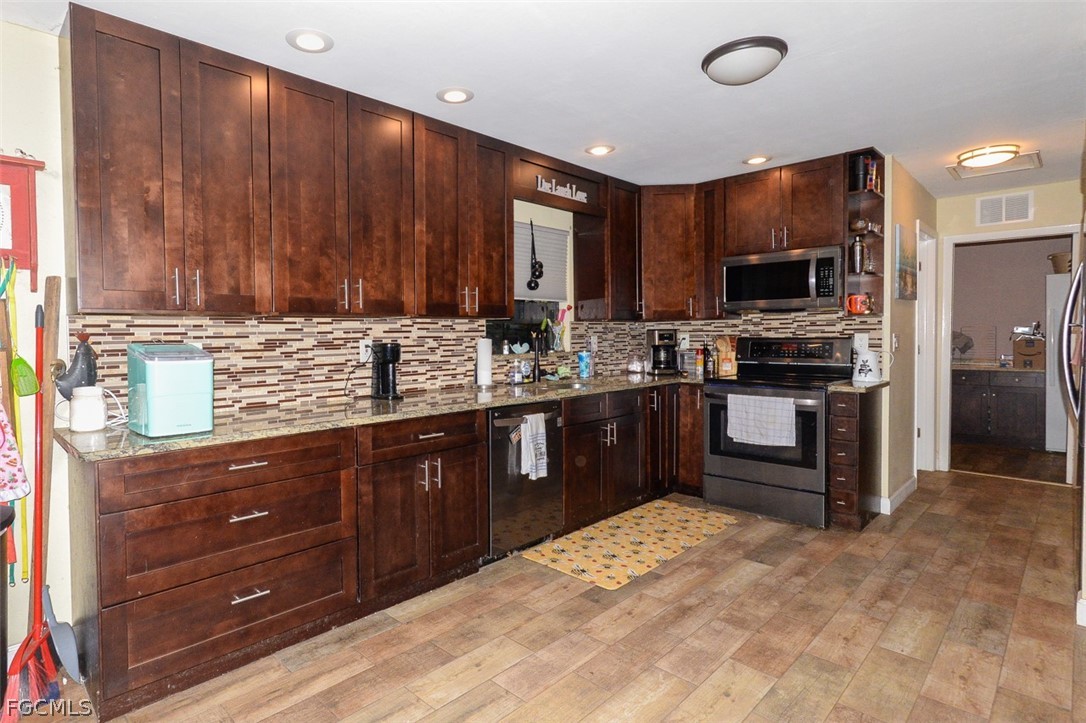 15581 Old Olga Road Alva, FL 33920 - Photo 8 of 38 a kitchen with stainless steel appliances granite countertop wooden cabinets a stove top oven a sink and dishwasher
