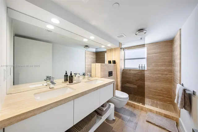 a bathroom with a double vanity sink toilet mirror and shower