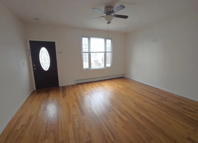 a view of empty room with wooden floor and fan