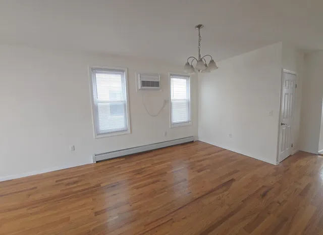 an empty room with wooden floor windows and cabinet