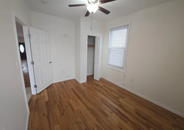 a view of empty room with wooden floor and fan