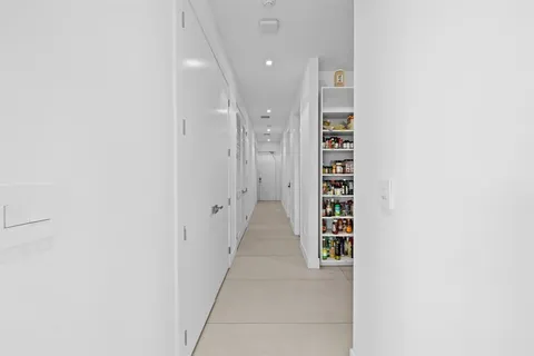 a view of a hallway with white walls and a window