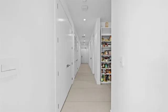 a view of a hallway with white walls and a window