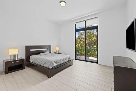 a spacious bedroom with a bed and a flat tv screen next to a window