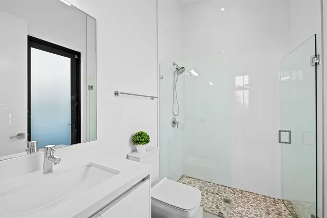 a bathroom with a granite countertop sink a toilet a mirror and shower