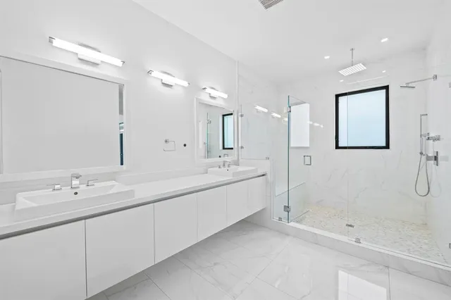 a spacious bathroom with a double vanity sink mirror and shower