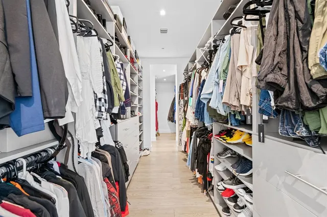 a view of walk in closet with clothes and shoes