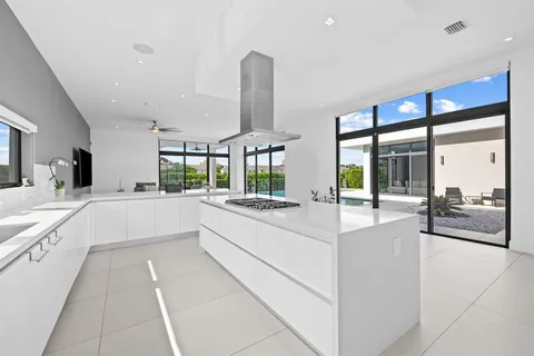 a large white kitchen with a large window and stainless steel appliances