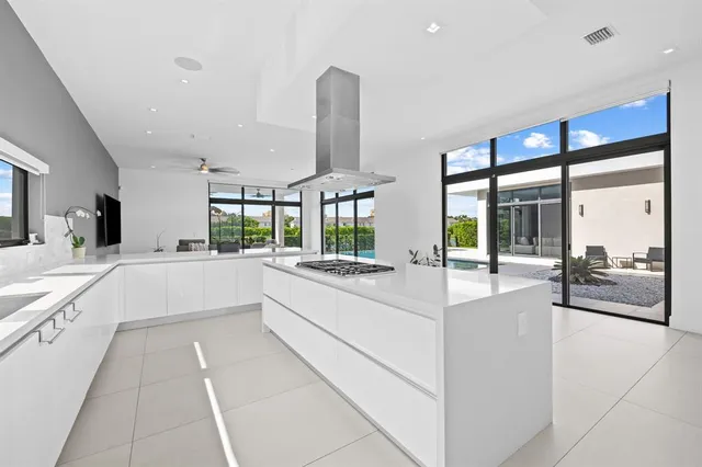 a large white kitchen with a large window and stainless steel appliances