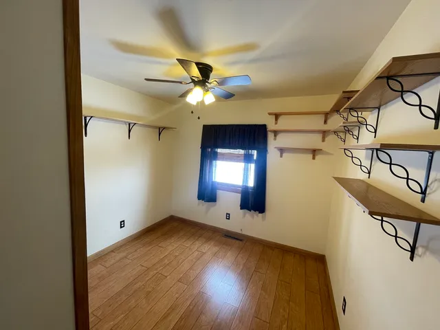 a view of an empty room with a window and wooden floor