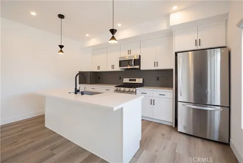 a kitchen with kitchen island a white counter top space wooden floor and appliances