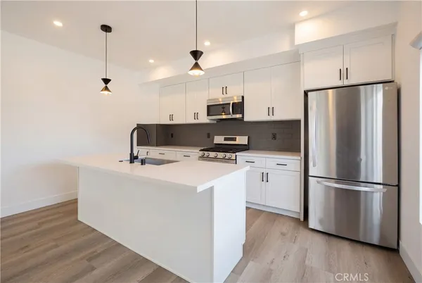a kitchen with kitchen island a white counter top space wooden floor and appliances