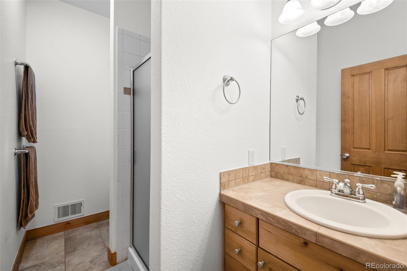 27711 Moffat Road Evergreen, CO 80439 - Photo 22 of 30 a bathroom with a sink a light fixture and a mirror