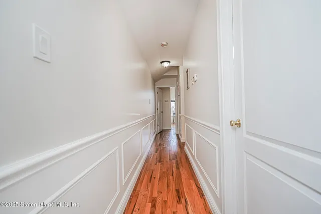 a view of a hallway with wooden floor and a bathroom