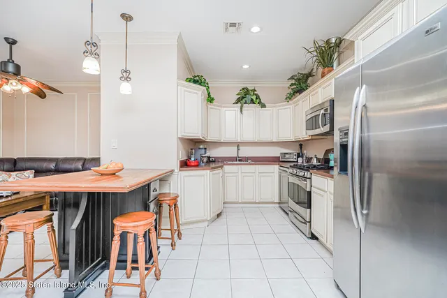 a kitchen with stainless steel appliances kitchen island granite countertop a table chairs and a refrigerator