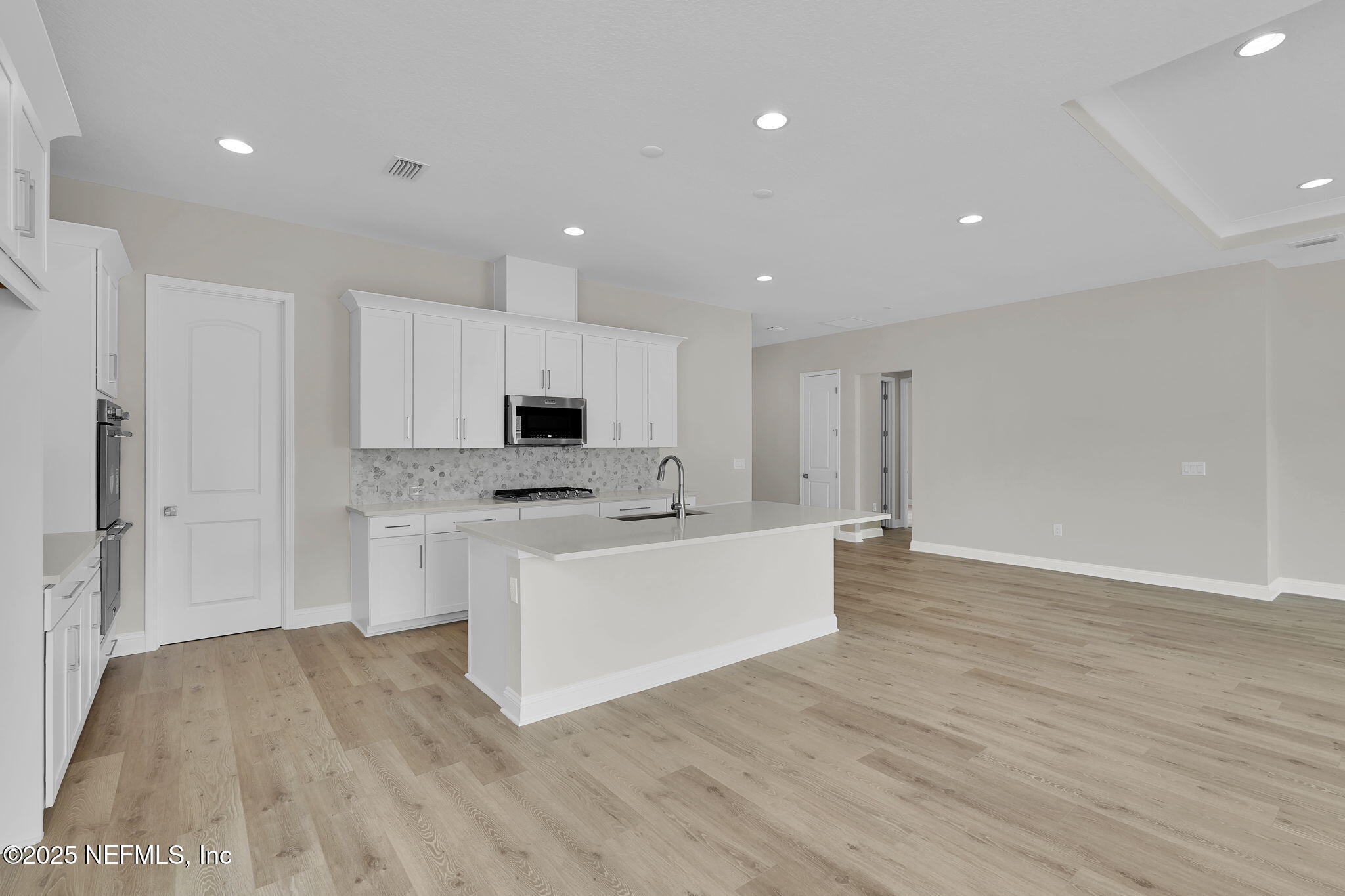 323 Sawgrass Drive Yulee, FL 32097 - Photo 21 of 48 a large white kitchen with white cabinets and wooden floor
