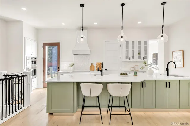 a kitchen with stainless steel appliances granite countertop a sink a stove a refrigerator and white cabinets with wooden floor