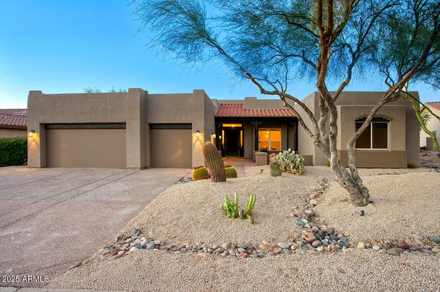 a front view of a house with a dirt yard and a large tree