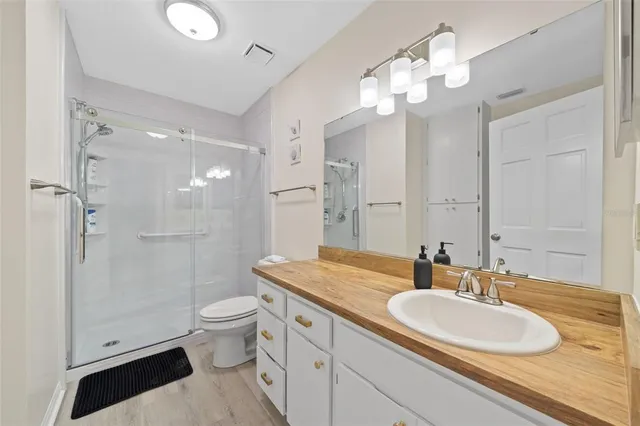 a bathroom with a granite countertop double vanity sink a mirror and a shower