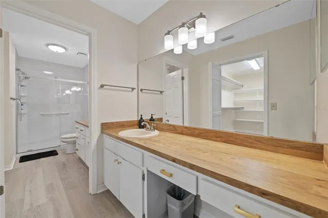 a spacious bathroom with a granite countertop sink a toilet a mirror and shower