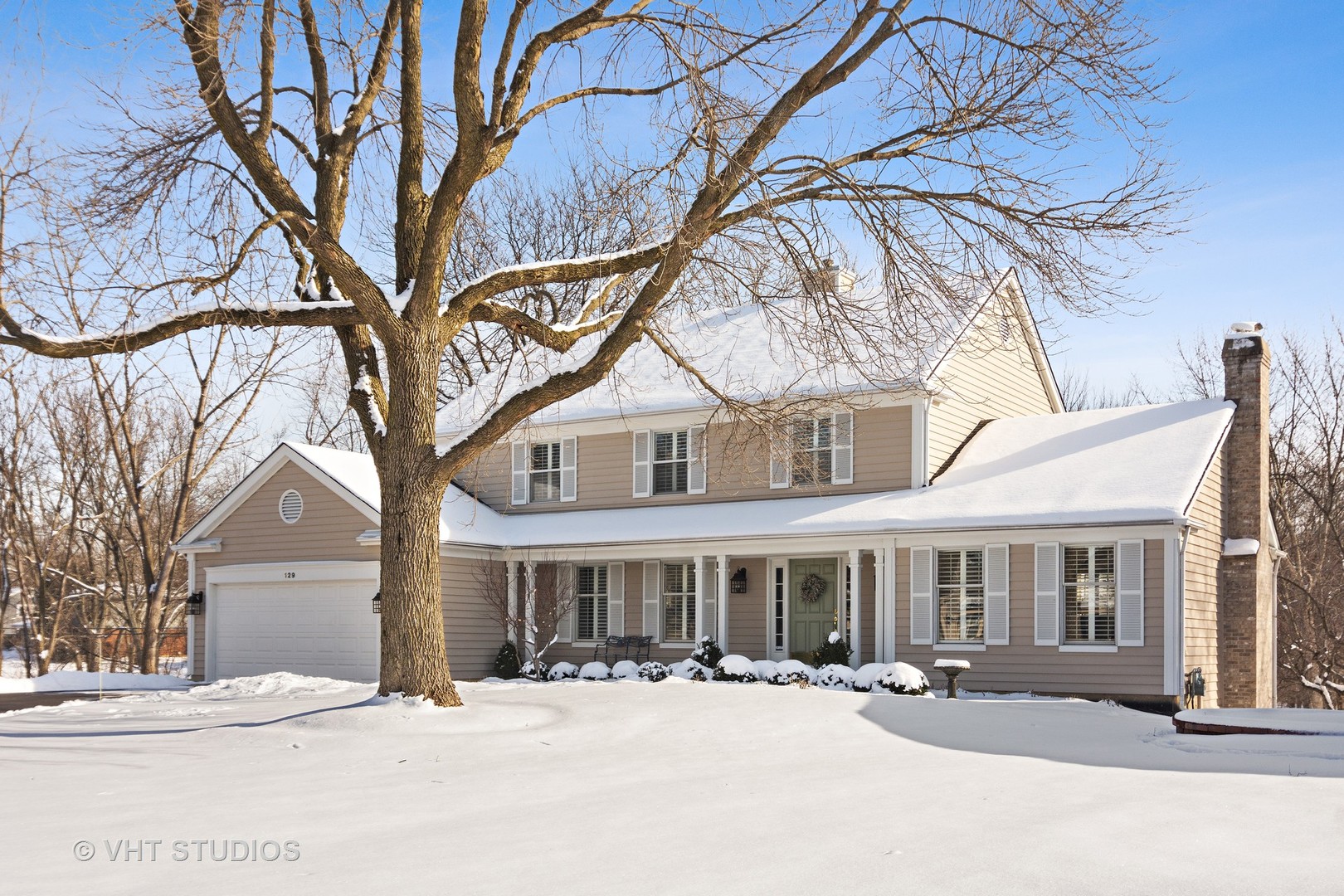 a front view of a house with a yard covered with snow