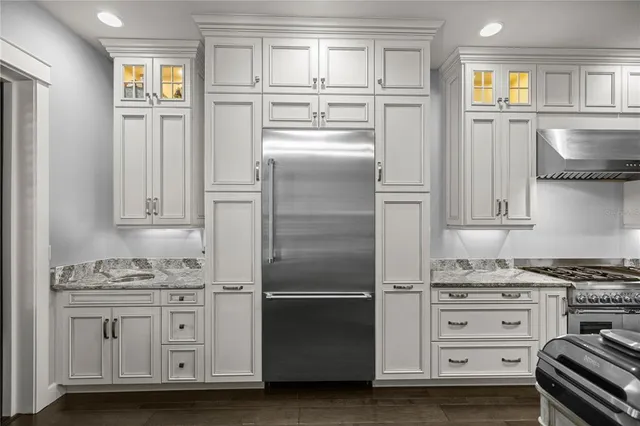 a kitchen with granite countertop a refrigerator stove and cabinets