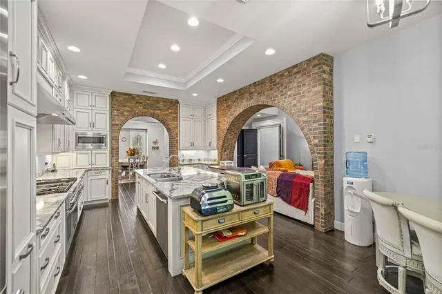 a living room with stainless steel appliances furniture a rug and a kitchen view