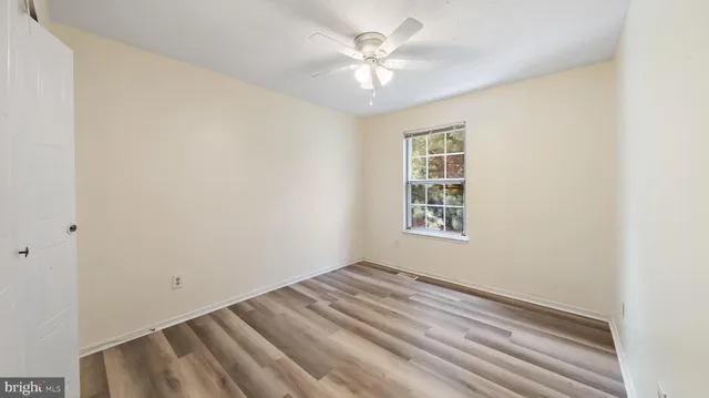 an empty room with windows and ceiling fan