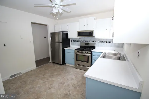 a kitchen with stainless steel appliances a stove a sink a refrigerator white cabinets and a refrigerator