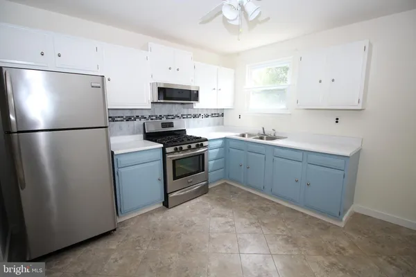 a kitchen with stainless steel appliances a refrigerator sink and white cabinets