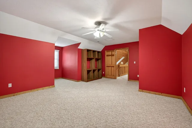 a view of an empty room with chandelier fan and fire place