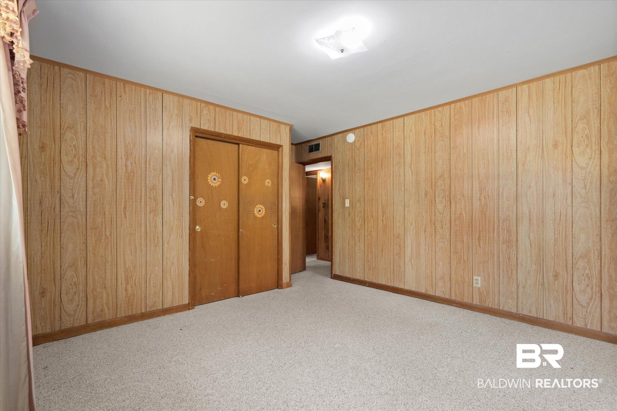 423 First Avenue Saraland, AL 36571 - Photo 11 of 20 Unfurnished bedroom featuring a closet, wood walls, and carpet floors