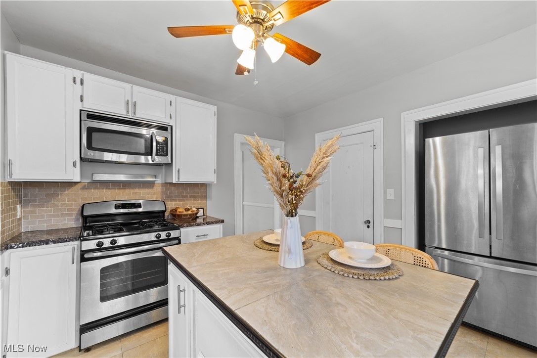 2891 Huntington Road Cleveland, OH 44120 - Photo 17 of 44 Kitchen with light tile patterned floors, stainless steel appliances, decorative backsplash, white cabinets, and ceiling fan