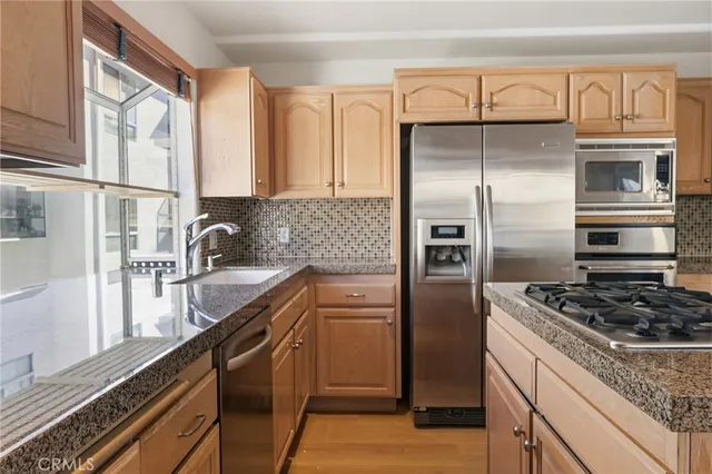 a kitchen with granite countertop stainless steel appliances a refrigerator a stove a sink and cabinets