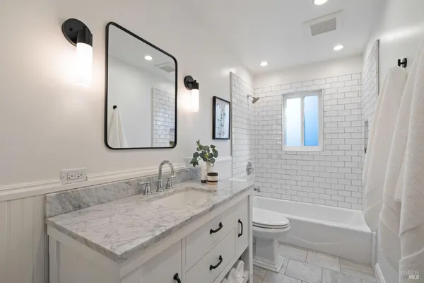 a bathroom with a granite countertop sink a toilet a mirror and shower
