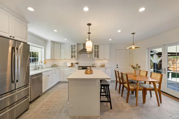 a kitchen with stainless steel appliances kitchen island granite countertop a table chairs and a refrigerator