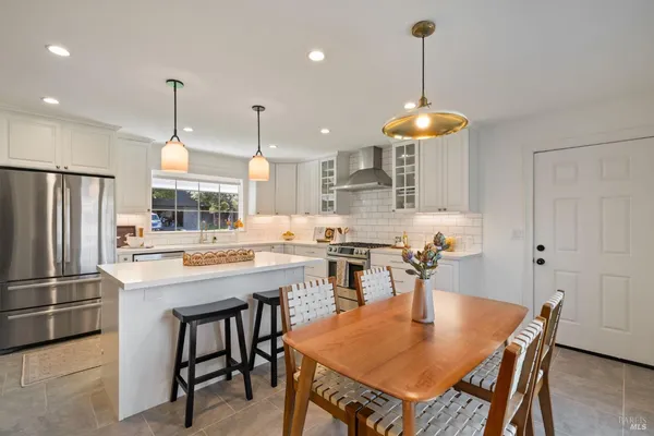 a kitchen with a dining table chairs stainless steel appliances and cabinets