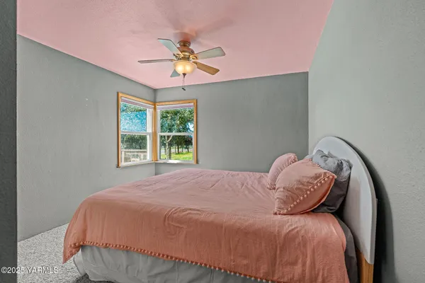 a bed sitting in a spacious bedroom next to a window