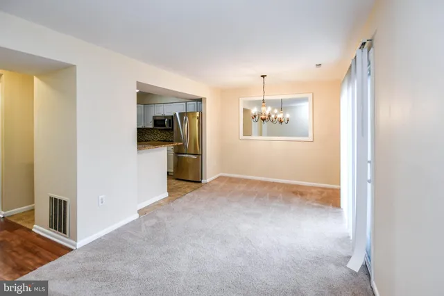 a view of a hallway with wooden floor and a kitchen
