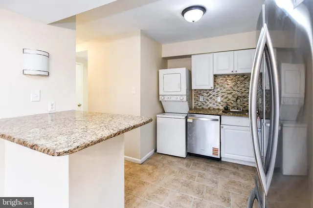 a kitchen with white cabinets and refrigerator