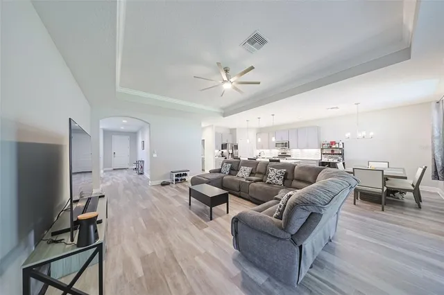 a living room with furniture a ceiling fan and a flat screen tv