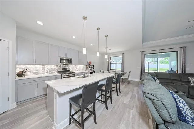 a kitchen with stainless steel appliances granite countertop a stove a sink a dining table and chairs with wooden floor