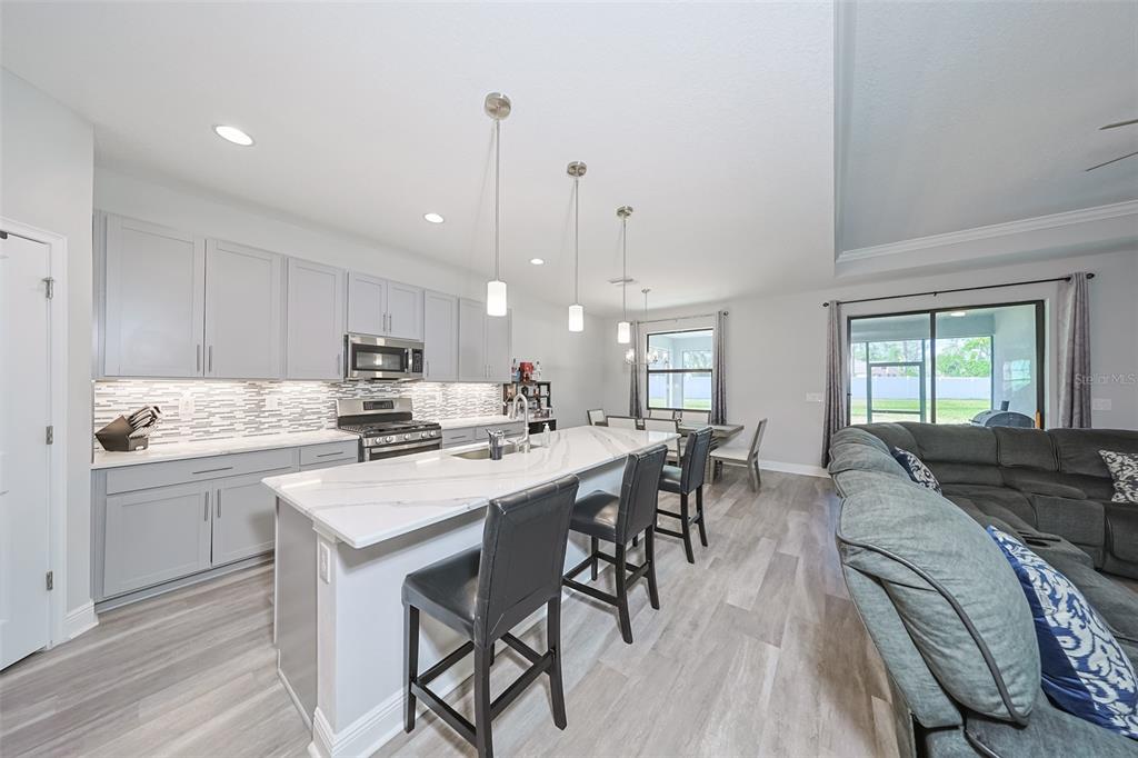 130 Azul Drive Seffner, FL 33584 - Photo 14 of 47 a kitchen with stainless steel appliances granite countertop a stove a sink a dining table and chairs with wooden floor