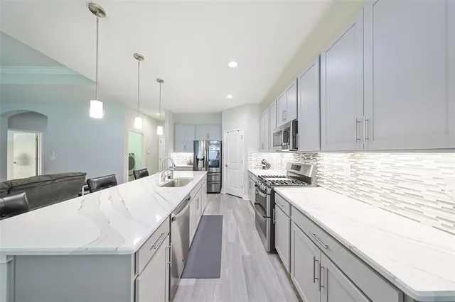 a kitchen with stainless steel appliances kitchen island granite countertop a sink a stove and a wooden floors