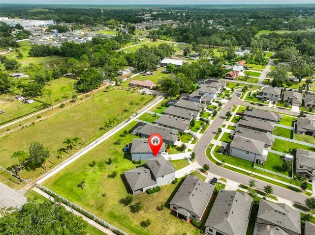 an aerial view of a residential houses with outdoor space and trees
