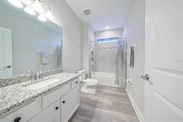 a bathroom with a granite countertop sink toilet a large mirror a shower and a bathtub