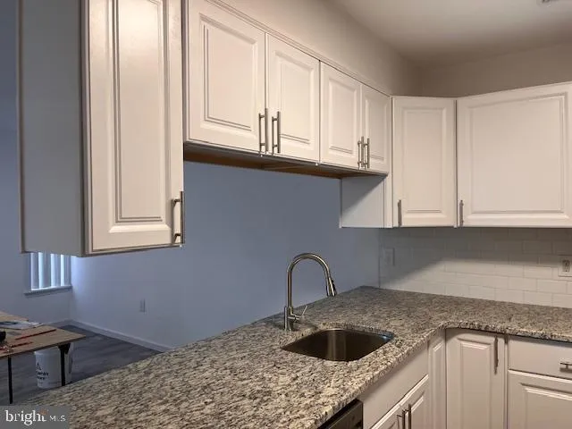 a kitchen with granite countertop white cabinets and a sink