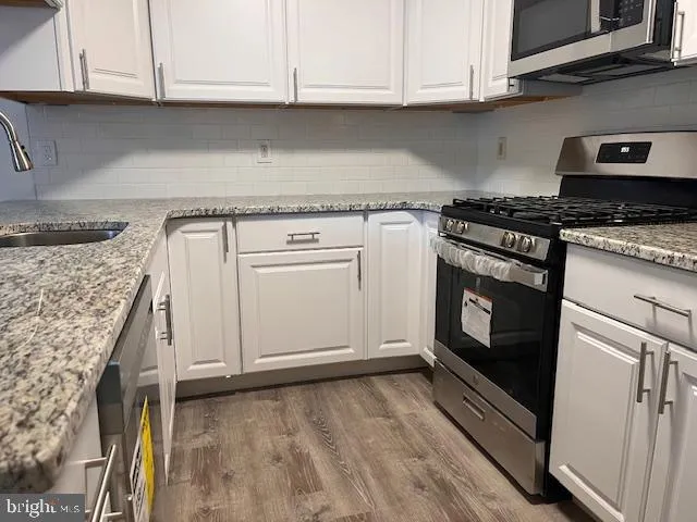 a kitchen with granite countertop cabinets stainless steel appliances and wooden floor