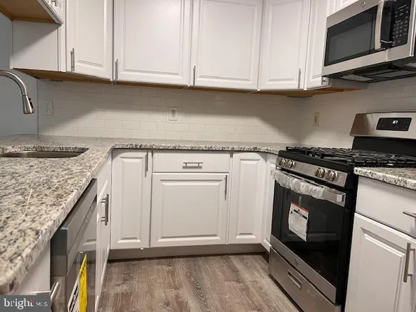 a kitchen with granite countertop cabinets stainless steel appliances and a sink